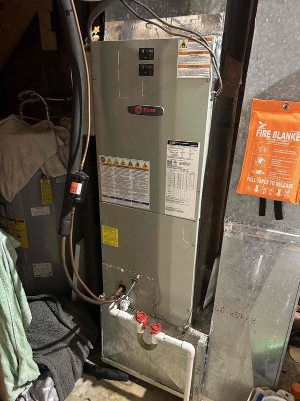 Responded to no cooling call on 9-year-old Trane heat pump system with outdoor condenser unit and basement-located air handler. Performed comprehensive diagnostic evaluation of both indoor and outdoor components to determine cause of system failure. Inspected electrical connections, refrigerant lines with service valves, condenser coil condition, and air handler operation. Unit showed no visible signs of physical damage or deterioration, with equipment appearing well-maintained on concrete pad with proper vibration isolation. Completed full system assessment and documented equipment condition with photographic records of outdoor condenser unit positioned against building foundation and indoor air handler installation in mechanical room.