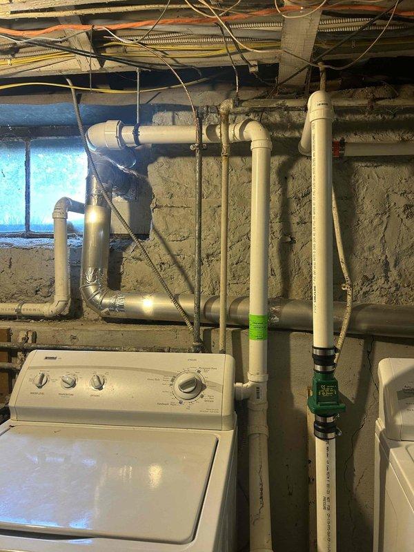 Provided plumbing estimate for rerouting sump pump discharge piping that currently runs through basement window. Assessment included evaluation of existing PVC drainage system, window replacement requirements, and proper exterior discharge routing to bring installation up to code while maintaining functional laundry room access.