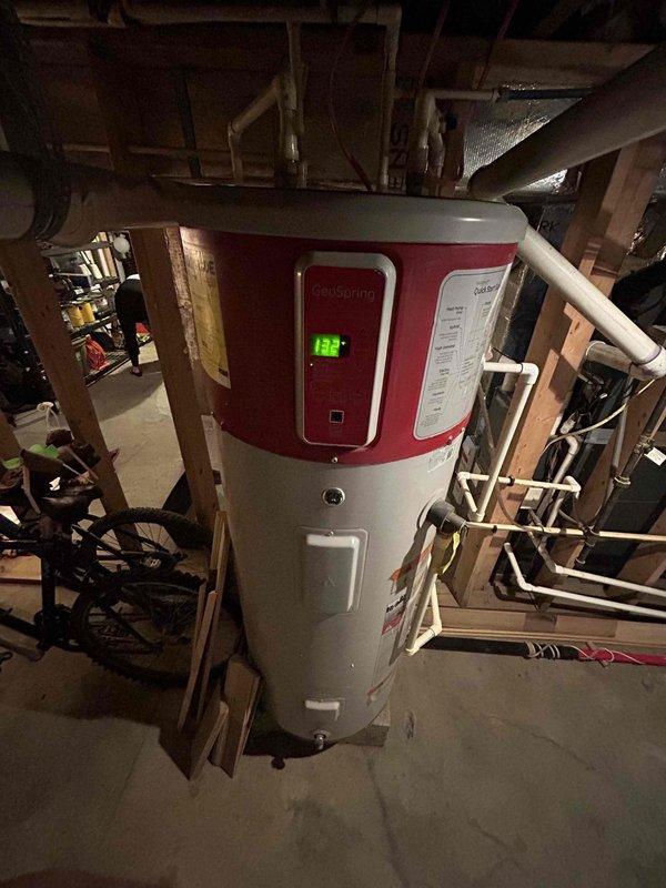 Completed comprehensive plumbing inspection of residential water heating system. Inspected GeoSpring hybrid electric water heater operating at 122°F, verified proper installation with PVC piping connections and confirmed valid plumbing permit approval from Division of Plumbing authority. All components found in satisfactory working condition with no deficiencies noted.
