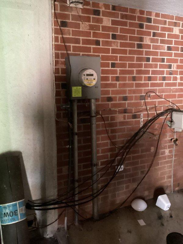 Conducted on-site electrical assessment for generator installation. Evaluated existing electrical infrastructure including main service panel with analog meter, conduit routing, and current circuit breaker configuration. Documented main distribution panel condition showing aged main breaker and multiple branch circuits with extensive wiring connections. Photographed meter base location on brick wall with existing conduit pathways to determine optimal connection points for proposed generator transfer switch. Assessed available panel capacity and identified necessary upgrades to accommodate automatic transfer switch integration with existing electrical system.