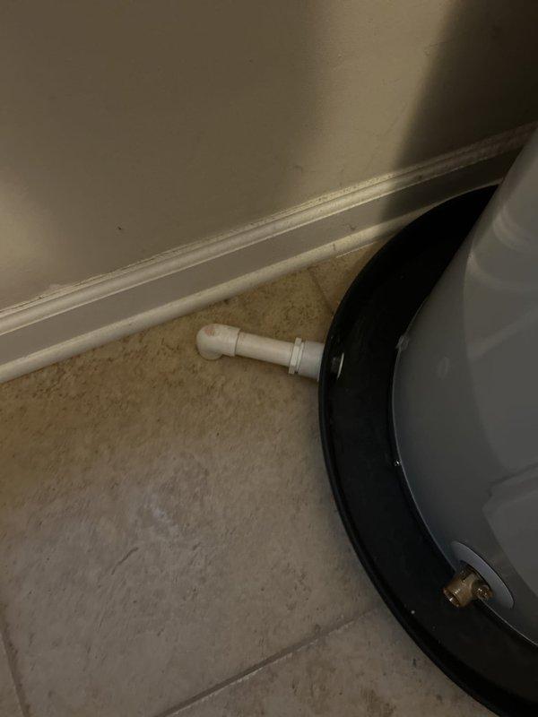 Completed repiping of drain pan discharge line to exterior of building. Installed new PVC drain line from air handler drain pan, routing through wall to terminate outside. Drain outlet now properly discharges condensate to exterior concrete pad, preventing indoor water damage. Verified proper drainage flow and secure pipe connections at both interior pan connection and exterior wall penetration.