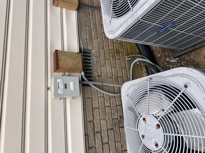 Responded to downstairs air conditioning unit freezing up and leaking water into basement with no cooling capability. Diagnosed failed thermal expansion valve (TXV) causing improper refrigerant metering and system icing. Provided comprehensive replacement estimate for air conditioning condenser unit and evaporator coil assembly due to age and condition of existing equipment, documenting outdoor dual-unit installation with photos showing both condenser units positioned on brick paver patio with electrical disconnects and refrigerant line sets properly installed on exterior wall.
