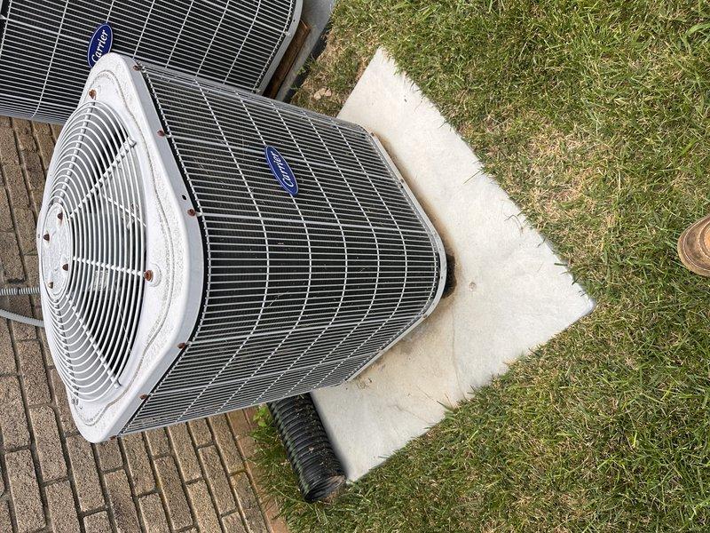 Responded to downstairs air conditioning unit freezing up and leaking water into basement with no cooling capability. Diagnosed failed thermal expansion valve (TXV) causing improper refrigerant metering and system icing. Provided comprehensive replacement estimate for air conditioning condenser unit and evaporator coil assembly due to age and condition of existing equipment, documenting outdoor dual-unit installation with photos showing both condenser units positioned on brick paver patio with electrical disconnects and refrigerant line sets properly installed on exterior wall.