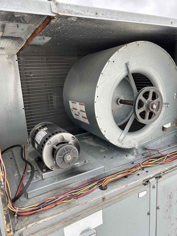 Responded to no cool call on commercial rooftop gas package unit (8-10 ton) with zoning issues affecting multiple zones. Upon inspection, discovered problematic wiring conditions in electrical control panel with disorganized wire routing and scattered fuses indicating previous service attempts or failures. Inspected blower assembly, belt drive system, and heat exchanger coil which showed signs of age with visible surface corrosion and dust accumulation. Diagnosed zoning malfunction related to control wiring and damper operation causing uneven cooling distribution throughout building. Performed system evaluation and documented existing conditions of electrical components, blower motor assembly, and internal cabinet components for repair recommendations.