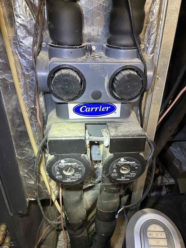 Responded to no cooling complaint on aging Carrier geothermal heat pump system. Upon inspection, found system operational but identified zone damper actuator requiring attention in the ductwork. Verified ground loop connections, circulation pumps, and indoor air handler components. Documented existing equipment configuration including dual pump setup and zone control damper system. System assessed and customer advised of findings.