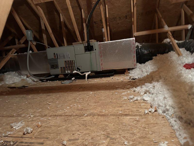 Conducted comprehensive site assessment for complete HVAC system replacement involving 2.5-ton Carrier heat pump system. Evaluated existing heat pump and air handler configuration with indoor unit located in attic space requiring ladder access for inspection. Documented current equipment conditions including attic-mounted air handler with flexible ductwork and exterior condensing unit positioned on weathered concrete pad against brick wall foundation. Photographed installation environment including attic structural framing, insulation coverage, equipment placement, and outdoor unit location with electrical disconnect and conduit routing. Provided detailed replacement estimate for new Carrier heat pump system sized appropriately for existing application.