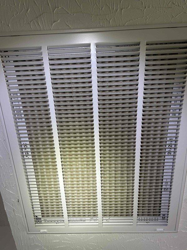Responded to water leak complaint at attic-mounted electric heat pump air handler system. Upon arrival, observed water damage at ceiling return air grille with visible staining and discoloration indicating prolonged moisture exposure during customer's absence. Inspected air handler unit and surrounding area, documenting conditions with photographs. Found condensate drain system with PVC drain line and brass valve assembly. Investigated source of water intrusion to determine cause of overflow condition. System evaluated for proper drainage function and potential blockages that may have caused backup during extended unattended operation period.
