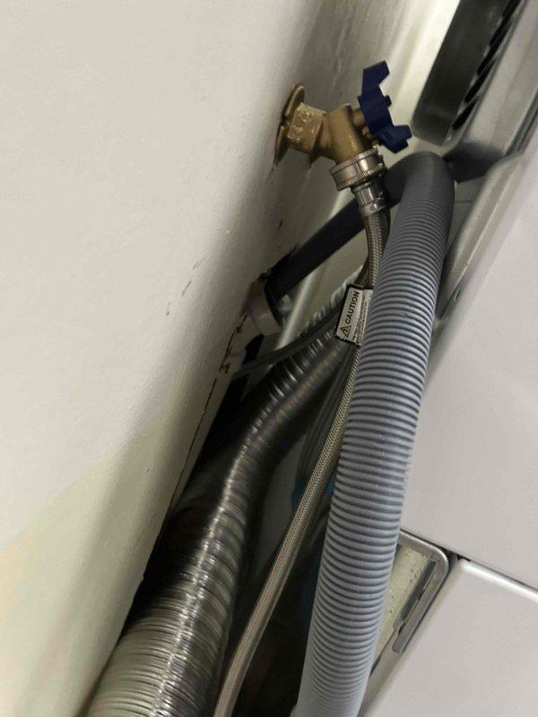 Responded to service call for water shut-off required prior to appliance installation. Located and operated existing brass quarter-turn ball valve with blue handle to isolate water supply. Verified proper shut-off function of valve controlling metallic braided stainless steel supply line and gray corrugated flexible hose connections, allowing safe disconnection for appliance replacement work to proceed.
