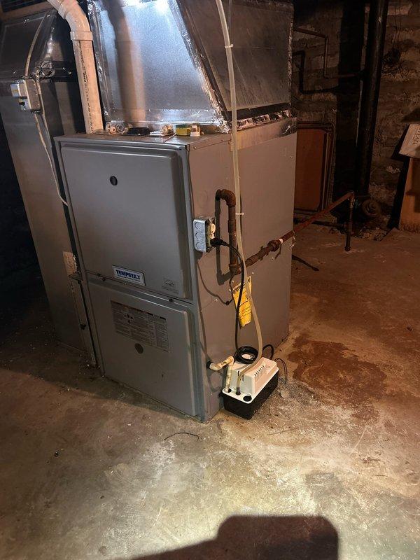 Responded to no cooling call affecting entire home. Upon arrival, inspected outdoor condensing unit and indoor air handler system. Outdoor unit showed signs of age and weathering with visible discoloration on top panel. Indoor equipment located in basement included furnace with connected air handler and auxiliary components. Performed diagnostic evaluation of complete HVAC system to identify cause of cooling failure. Documented equipment condition and configuration with photos for service records. System brand and age were unknown at time of service, though equipment showed moderate wear consistent with several years of operation.