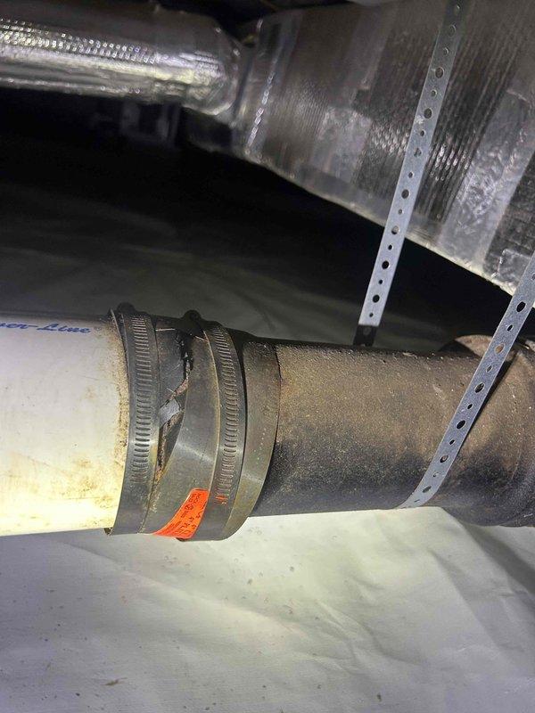 Responded to service call for broken pipe in crawl space. Upon inspection, discovered damaged black rubber coupling connecting ductwork sections had failed, causing separation of the joint. Removed deteriorated rubber connector with attached metal clamp and replaced with new coupling to restore proper connection. Secured all components with appropriate hose clamps and verified system integrity upon completion.