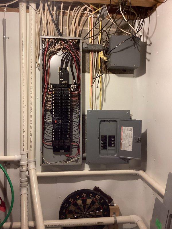 Completed electrical estimate for running new line to breaker panel in basement. Assessed existing electrical infrastructure including main breaker panel with multiple circuits, adjacent subpanel, and overhead conduit routing along exposed joists. Evaluated current panel capacity, wire gauge requirements, and optimal routing path for new circuit installation while maintaining code compliance and proper load distribution across existing breaker configuration.