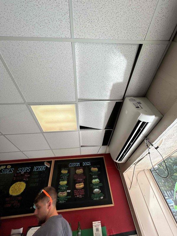 Responded to callback for mini split system leaking onto floor at commercial restaurant location. Upon inspection, identified severely deteriorated line set insulation on refrigerant lines above ceiling, with foam material completely crumbled and exposing copper piping that showed oxidation and corrosion. Documented existing conditions with photographs showing compromised insulation allowing condensation to form on exposed copper lines and drip through ceiling tiles onto floor below.