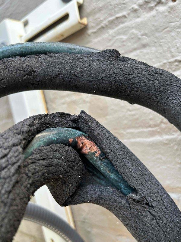 Responded to callback for mini split system leaking onto floor at commercial restaurant location. Upon inspection, identified severely deteriorated line set insulation on refrigerant lines above ceiling, with foam material completely crumbled and exposing copper piping that showed oxidation and corrosion. Documented existing conditions with photographs showing compromised insulation allowing condensation to form on exposed copper lines and drip through ceiling tiles onto floor below.