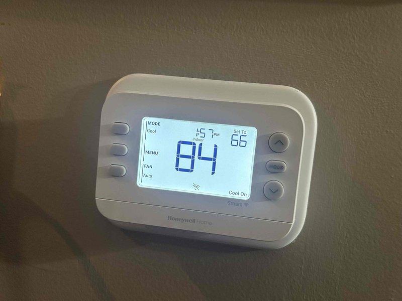 # HVAC Service Call - No Cooling Condition

Responded to service call for complete loss of cooling affecting entire residence. System is approximately one year old, still under manufacturer warranty period.

Upon arrival, verified thermostat set to cooling mode with setpoint at 66°F while indoor ambient temperature had risen to 84°F. Thermostat display indicated "Cool On" status with system calling for cooling. Confirmed thermostat wireless connectivity operational and fan set to auto mode.

Proceeded to outdoor unit for diagnostic inspection. Visually inspected condenser unit exterior and surrounding area. Noted drainage lines present at building foundation with adequate clearance, though vegetation management needed around utility penetrations.

Performed comprehensive system diagnostics including electrical connections, refrigerant pressures, and component operation. Identified root cause of no-cool condition and completed necessary repairs to restore system functionality. Cycled sy