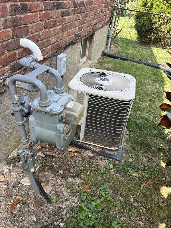 Responded to no cooling complaint with home temperature rising to 80-81°F instead of maintaining 78°F setpoint. Upon arrival, performed comprehensive system evaluation of split air conditioning system with aging outdoor condenser unit and recently replaced furnace. Conducted visual inspection of outdoor equipment positioned on concrete pad, noting weathered condenser unit with dirt accumulation on coil fins and cabinet surfaces. Inspected indoor air handler and furnace installation in mechanical room, verifying proper installation of ductwork and venting systems. Performed diagnostic testing to identify root cause of inadequate cooling capacity and inability to maintain desired temperature setpoint. Documented equipment conditions through photographic records showing outdoor condenser installation with associated plumbing components and indoor HVAC equipment configuration. Evaluated system operation and airflow characteristics to determine performance deficiencies affecting whole-house