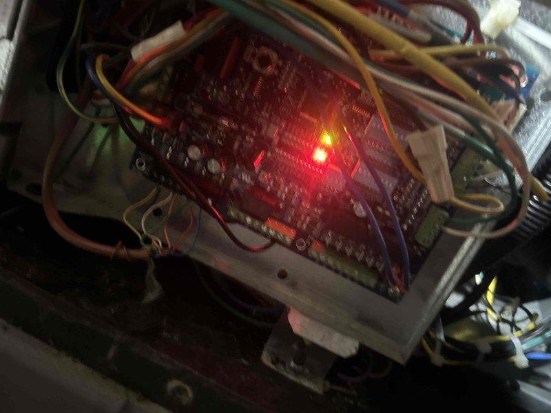 Responded to no cooling complaint on 8-year-old geothermal system blowing warm air. Performed diagnostic testing on control board and electrical components using multimeter to measure voltage and current at various connection points. Inspected PCB with illuminated status LEDs, traced multiple wire connections throughout control panel, and evaluated system operation. Identified issue with geothermal heat pump control system preventing proper cooling mode operation.