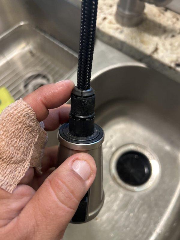 Responded to a kitchen faucet sprayer detachment issue where the pull-out nozzle assembly had separated from the main faucet body. Upon inspection, successfully reinstalled the sprayer head by reconnecting the quick-connect fitting at the base of the spray wand to the hose assembly. Verified proper seating of the cylindrical connector sleeve and tested spray function to ensure secure attachment and normal water flow operation.