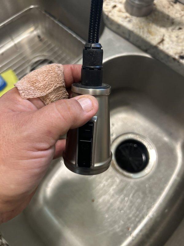 Responded to a kitchen faucet sprayer detachment issue where the pull-out nozzle assembly had separated from the main faucet body. Upon inspection, successfully reinstalled the sprayer head by reconnecting the quick-connect fitting at the base of the spray wand to the hose assembly. Verified proper seating of the cylindrical connector sleeve and tested spray function to ensure secure attachment and normal water flow operation.