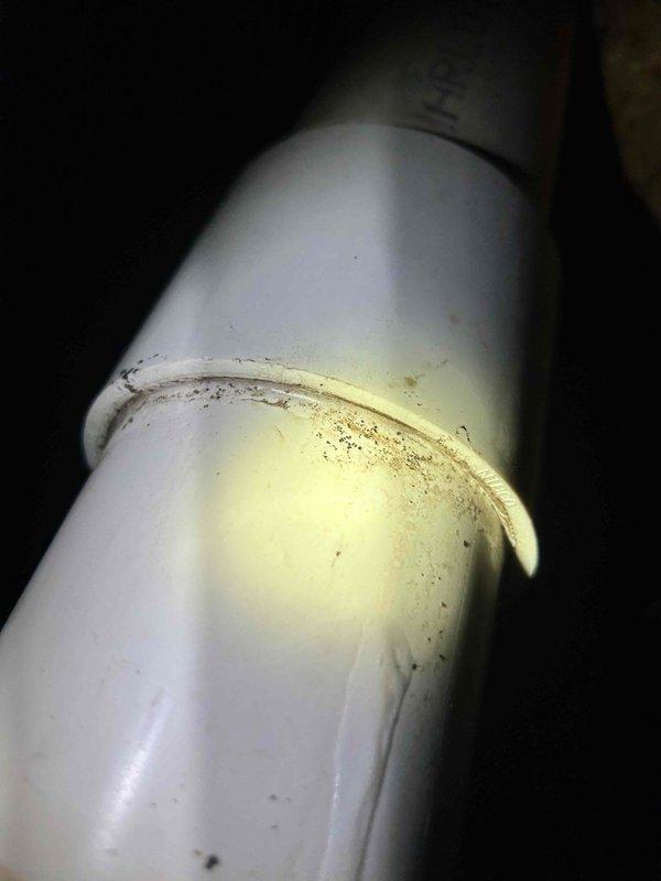 Responded to report of pipe leaking in attic during rainfall, initially identified by HVAC contractor during recent installation. Upon inspection, located vertical pipe system running through attic framing with visible signs of moisture intrusion and residue accumulation on PVC sections. Examined multi-segment pipe assembly consisting of copper, gray, and white PVC components joined with metal bands and secured with perforated metal hangers. Documented extensive discoloration and debris buildup around pipe joints, indicating prolonged exposure to water and potential leak points. Photographed affected areas showing yellowed residue and grime accumulation on pipe surfaces. Assessed structural framing and surrounding areas for water damage. Provided diagnostic findings and recommendations for repair.
