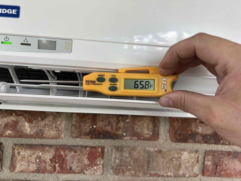 Responded to service call for ductless mini-split system with no cooling or heating capability and unresponsive control interface. Upon arrival, found wall-mounted indoor unit installed in enclosed porch area. Performed diagnostic evaluation of system, including temperature measurements at discharge vents which registered 65.8°F. Inspected control panel functionality and verified power supply to unit. Documented equipment condition and current operational status with photographic evidence for service records.