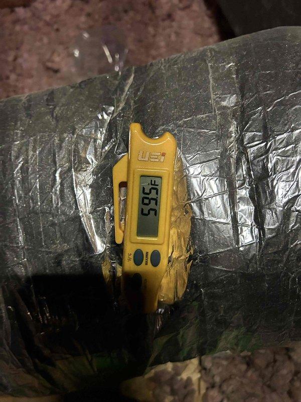 Responded to no cooling call on 4-year-old electric heat pump system with indoor unit located in garage. Performed diagnostic assessment of reported refrigerant leak and evaporator coil issue. Evaluated airflow concerns at multiple supply vents and investigated condensation problem at return air intake. Measured supply air temperature at 55.5°F and return air temperature at 66.2°F, confirming reduced cooling capacity and inadequate temperature split. Inspection revealed compromised airflow delivery through ductwork system, likely contributing to condensation issues and weak air distribution throughout living space. Documented current system conditions with thermal measurements at supply and return ducts in attic space.