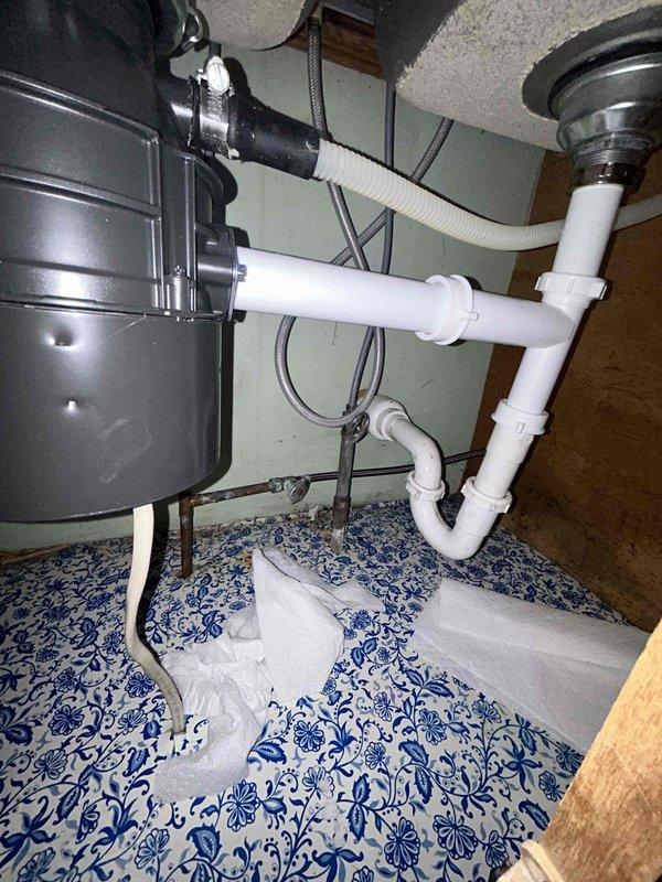 Responded to service call for leak at recently installed kitchen faucet in 65-year-old residence. Upon arrival, inspected chrome dual-handle faucet with arched spout and separate spray nozzle mounted on double-basin stainless steel sink. Identified source of leak and tightened supply line connections beneath sink. Examined under-sink plumbing configuration including P-trap assembly, garbage disposal unit with corrugated drain hose, and supply valves to ensure proper sealing and connection integrity. Tested faucet operation at multiple flow rates and verified all connections remained dry under pressure. Confirmed leak was resolved and no additional plumbing issues were present in the immediate area.