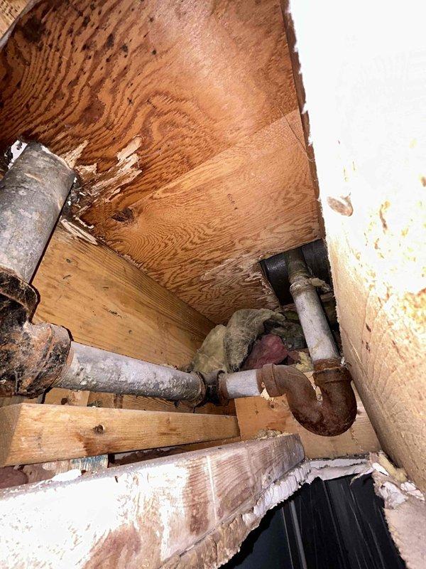 Responded to a plumbing service call for a broken tub diverter and damaged pipe that had been problematic for several years in a 65-year-old home. Upon inspection, accessed the crawl space beneath the bathroom and documented the existing plumbing infrastructure, which consisted of severely corroded galvanized steel piping showing extensive deterioration, rust, and surface degradation consistent with the age of the home. The affected pipes displayed significant wear from prolonged moisture exposure, with visible corrosion at connection points and deteriorated metal surfaces throughout the drainage system. Photographed the compromised plumbing assembly including the P-trap configuration and vertical drainage pipes to document the extent of deterioration and provide recommendations for repair or replacement of the aging galvanized piping system.