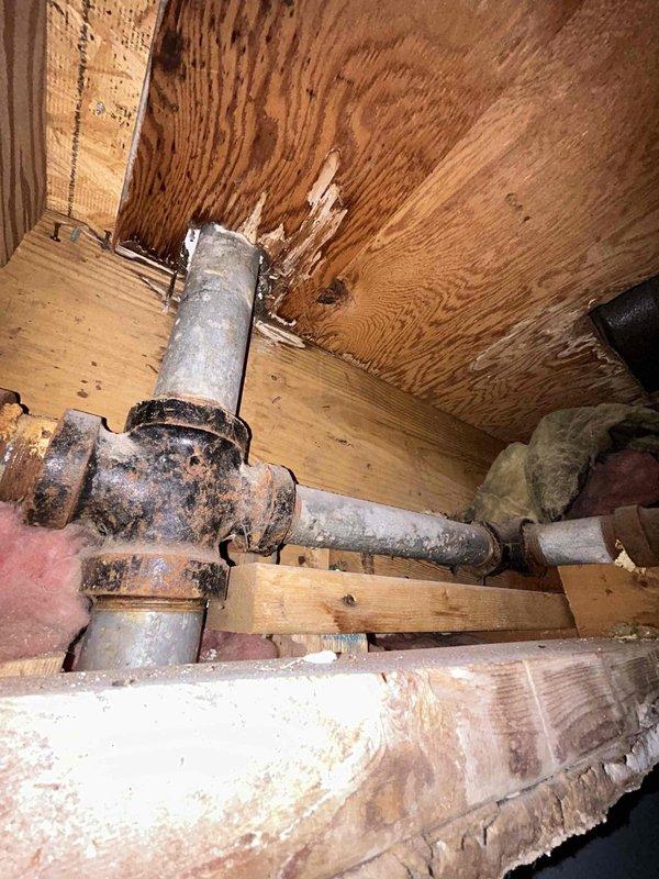 Responded to a plumbing service call for a broken tub diverter and damaged pipe that had been problematic for several years in a 65-year-old home. Upon inspection, accessed the crawl space beneath the bathroom and documented the existing plumbing infrastructure, which consisted of severely corroded galvanized steel piping showing extensive deterioration, rust, and surface degradation consistent with the age of the home. The affected pipes displayed significant wear from prolonged moisture exposure, with visible corrosion at connection points and deteriorated metal surfaces throughout the drainage system. Photographed the compromised plumbing assembly including the P-trap configuration and vertical drainage pipes to document the extent of deterioration and provide recommendations for repair or replacement of the aging galvanized piping system.