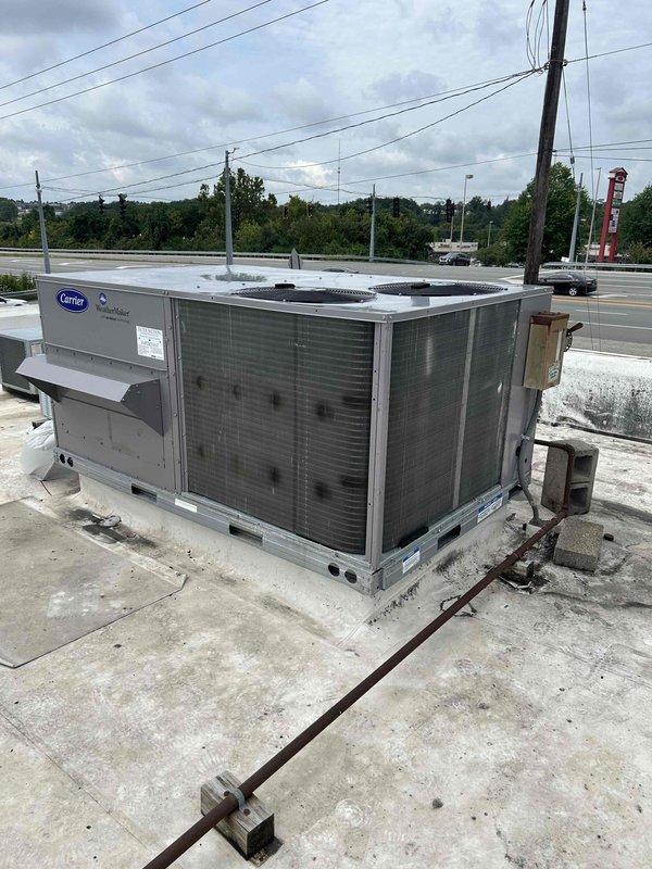 Completed commercial rooftop unit replacement on a flat roof concrete pad, installing client-provided Carrier WeatherMaker packaged air conditioning system utilizing crane services for safe placement. Integrated miscellaneous connection materials including electrical conduit, drainage components, and mounting hardware to secure the RTU to the rooftop surface. All work performed to manufacturer specifications with one-year labor warranty provided on the installation.