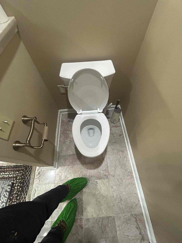 Responded to service call for unstable toilet that was rocking and moving during use. Upon inspection, removed toilet to access the flange and discovered a deteriorated toilet flange with significant wear, staining, and compromised structural integrity. The existing flange showed brown discoloration and degradation around the mounting area, which was causing the toilet to lose its secure connection to the floor. Documented the condition of the damaged flange and surrounding tile flooring for repair assessment.