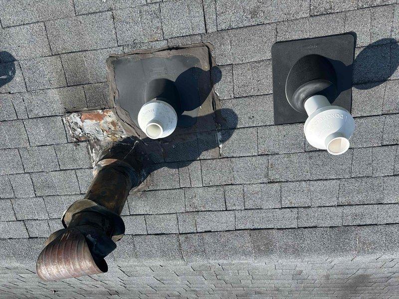 Replaced deteriorated concentric vent kit on roof due to active water intrusion that was initially suspected to be an old stain but confirmed to be an active leak. Relocated vent penetration approximately 5 feet from original position, drilled new roof penetration, and installed new concentric vent kit with proper flashing and sealing. Removed old damaged flashing and vent components showing significant weathering, rust, and compromised rubber boot deterioration. Secured roof area with tarp for temporary weather protection until roofing contractor can return to install shingles over new flashing and repair original penetration location.