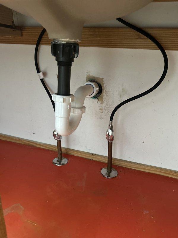 Technician successfully installed two customer-provided bathroom sink faucets in a 1980s-built home following countertop replacement. Installation included mounting single-handle brushed nickel faucets to new white quartz countertops with undermount sinks, connecting hot and cold water supply lines with flexible hoses, and installing drain assemblies with P-trap configurations. Both faucet installations were tested for proper operation and checked for leaks, with all connections secured and functioning correctly.