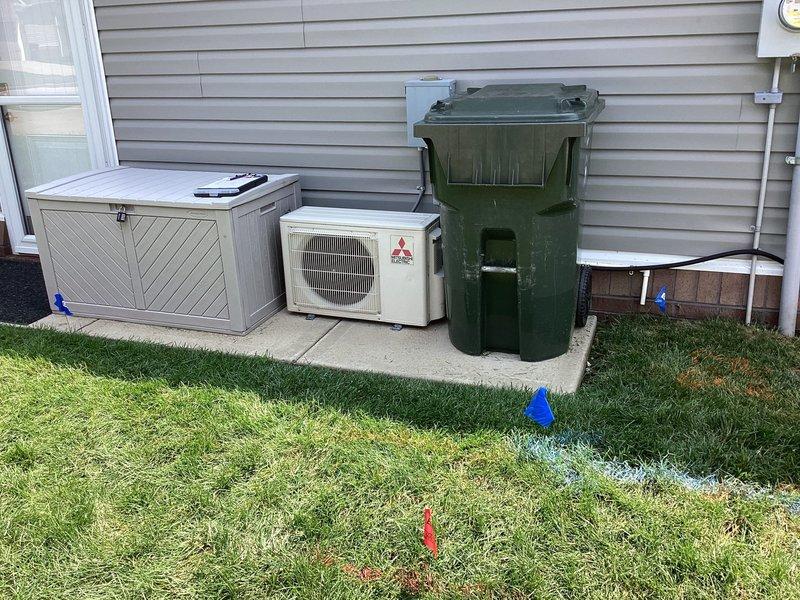 Conducted comprehensive electrical site assessment for standby generator installation at residential property. Evaluated existing 200-amp main electrical panel with dual-column breaker configuration to determine load capacity and optimal integration point for automatic transfer switch. Documented current electrical infrastructure including circuit distribution and panel condition. Assessed exterior installation location adjacent to HVAC condenser unit on concrete pad, noting adequate clearance from structure and accessibility for fuel line connection and maintenance access. Verified utility marking flags indicating safe excavation zones for electrical conduit routing and potential gas line installation from meter to proposed generator location.