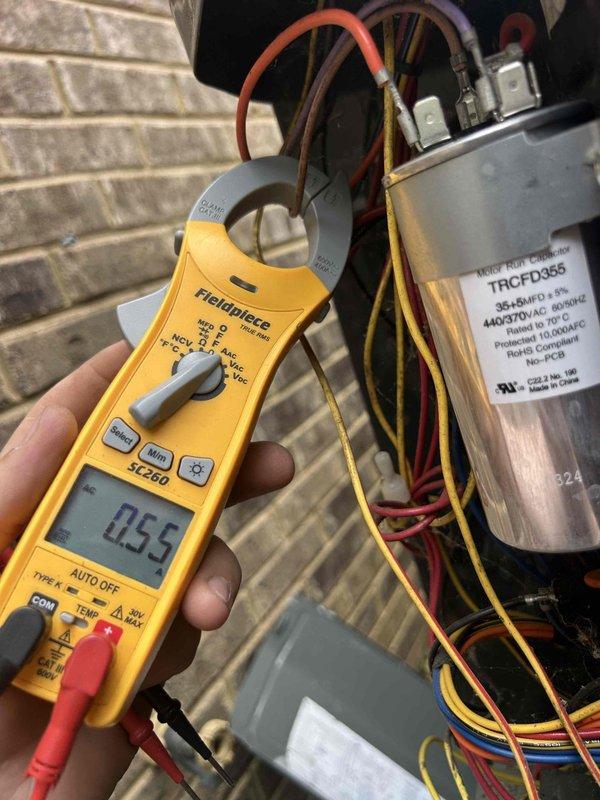 Responded to service call for thermostat not maintaining setpoint of 74 degrees. Performed diagnostic evaluation of HVAC air handler unit located in attic space. Utilized Fieldpiece SC260 clamp meter to measure electrical current and voltage at capacitor terminals, recording 0.55 amp reading. Inspected air handler cabinet, ductwork connections, and associated electrical components including motor run capacitor rated at 5.0 µF 440/370V. Documented equipment condition and system operation with photographs for service records.