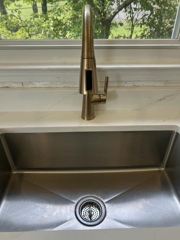 Reconnected kitchen sink plumbing assembly that had been previously disconnected. Installed P-trap configuration with chrome tailpiece and white PVC drain lines, ensuring proper alignment and secure connections to wall drain. Verified all fittings were leak-free and drain flow was functioning correctly.