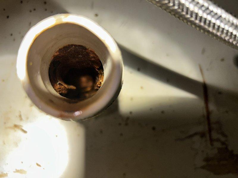 Responded to recurring kitchen sink drain clog in a 1974-built home with suspected pipe damage approximately 20 feet downstream under concrete slab. Upon arrival, assessed access options and determined roof vent access was feasible, eliminating the need to work through the kitchen sink fixture inside the home. Deployed sewer camera through roof vent to locate and identify the obstruction and confirm suspected pipe deterioration in the underground section. Utilized drain snake equipment via roof vent access point to clear the blockage affecting the kitchen drain line. Successfully restored proper drainage flow and documented findings with photographic evidence showing significant mineral buildup and rust-colored deposits within the drain system, consistent with aging cast iron or galvanized piping typical of the home's construction era. Communicated findings and completion status to customer via phone as requested.