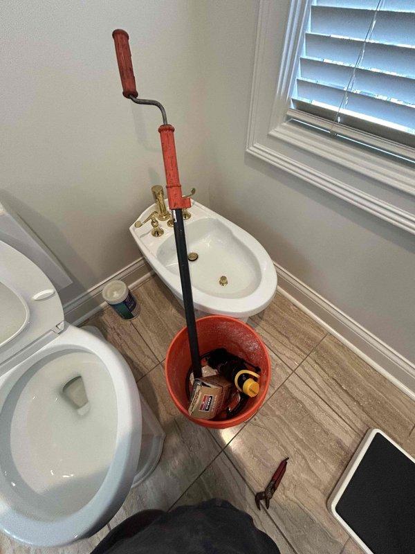 Responded to service call for toilet stoppage issue. Upon arrival, assessed the toilet and determined a clog was present in the drain line. Utilized manual drain auger to clear the obstruction from the toilet trap and drain system. Successfully removed blockage and restored proper drainage function. Inspected toilet tank components including flush valve assembly, fill valve, and flapper mechanism to ensure all internal parts were operating correctly. Verified water level and flush operation were within normal parameters. Tested toilet multiple times to confirm complete clearance of stoppage and proper waste evacuation. Left fixture in full working order with no further issues detected.