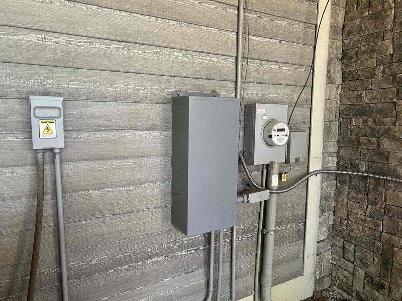 Responded to service call for Generac generator repeatedly tripping fuses. Performed diagnostic inspection of exterior-mounted electrical service equipment including disconnect panel, meter base, and associated conduit connections. Inspected attic-mounted transfer switch and related electrical components. Documented equipment configuration with photographs and applied service stickers as required.