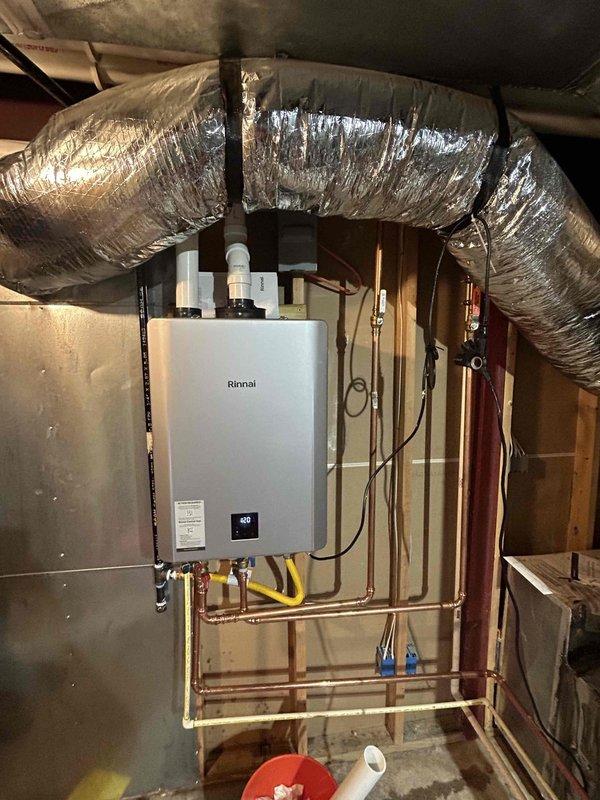 Removed existing tank-style water heater and installed customer-supplied Rinnai tankless water heater unit. Ran necessary gas piping including flexible yellow gas line connections to accommodate the new tankless system requirements. Installed copper water supply lines with shut-off valves (red and blue handled) and completed all plumbing connections to the unit. Mounted unit securely to wall framing and connected electrical wiring. Configured digital display and verified proper operation showing temperature reading of 105 degrees. Note: Tech to return for follow-up visit to install comfort valve and activate built-in recirculating pump for hot water recirculation system.