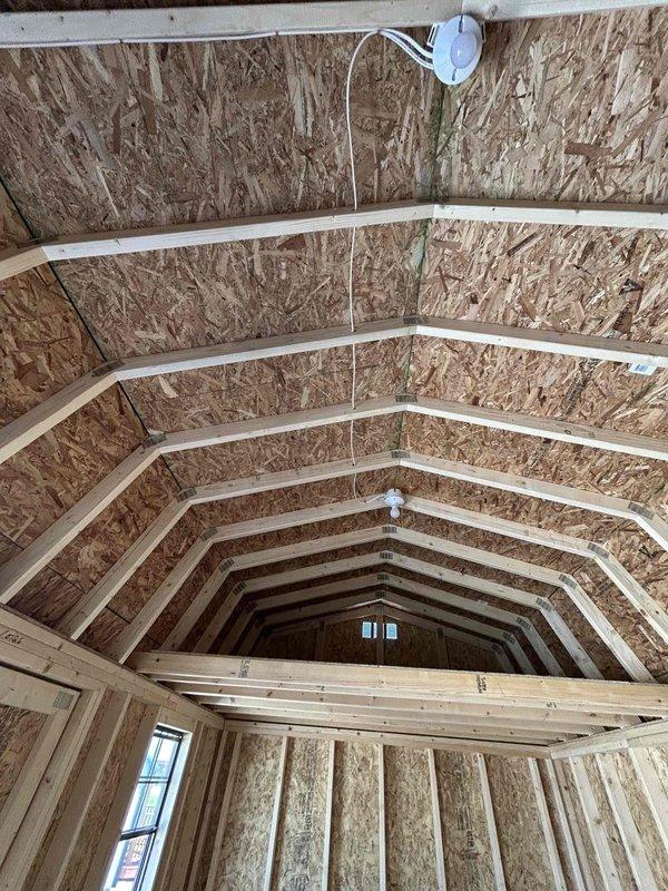 Completed electrical rough-in installation for commercial space under construction, installing one GFCI receptacle, one standard duplex receptacle, two single-pole switches, one keyless light fixture with bulb, and one SJ cord with male cord cap. All devices were wired according to NEC standards in the exposed stud framing of the unfinished interior space featuring vaulted ceiling construction.