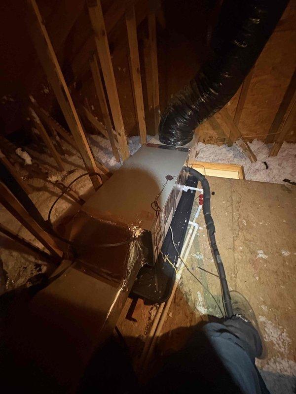 Completed full HVAC system installation in attic consisting of Lennox ML14KP1-024 2-ton single stage heat pump outdoor unit, CBK45UHET-024 constant torque air handler, and 10KW electric heat kit with S200 thermostat. Installed outdoor unit on new pad with snow legs, electrical disconnect box, and electrical whip kit. Applied refrigerant line insulation and installed refrigerant line filter on copper lines connecting outdoor and indoor units. Mounted air handler in attic with transition connections to existing ductwork and installed standard-sized air filter rack for system maintenance access.

Installed complete condensate drainage system including P-trap configuration with PVC piping, SS2 coil drain safety water sensor, and "Ceiling Saver" overflow drain pan equipped with secondary water sensor for leak protection. All drainage components positioned in black secondary drain pan as photographed. Obtained applicable permits and ensured all work met code compliance standards. Removed and