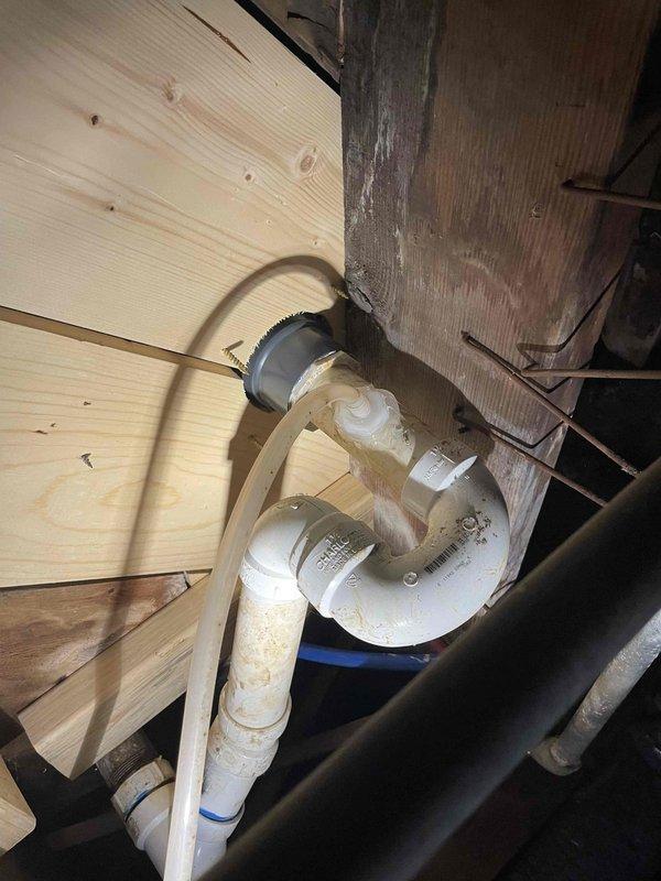 Responded to kitchen sink line backup at 68-year-old residence. Previous snaking attempt by homeowner had reached approximately 25 feet without clearing the obstruction. Upon arrival, assessed the existing plumbing configuration in the crawl space, which consisted of white PVC drainage pipes with multiple elbows and connections showing age-related discoloration. Determined that blockage was located beyond the initial 25-foot reach. Utilized extended cable equipment to access and clear the clog in the main drain line. Successfully restored proper drainage flow to the kitchen sink. Inspected all visible pipe connections and joints in the crawl space for leaks or damage during the clearing process. Verified complete water flow and drainage functionality upon completion.