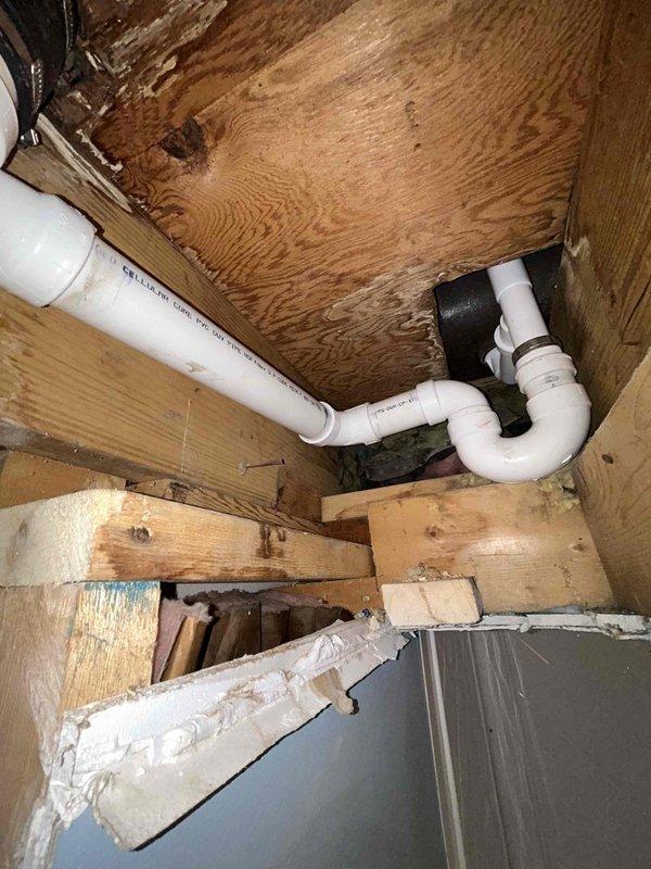 Completed under-sink plumbing repair in residential bathroom, removing existing drain assembly and P-trap. Installed new white PVC drain assembly with proper trap configuration, utilizing black rubber coupling to connect pipe sections. Accessed plumbing through cabinet opening, working within confined space beneath sink structure. Following installation, conducted thorough leak test to verify proper seal and drainage function. All connections secured and system restored to full operation.