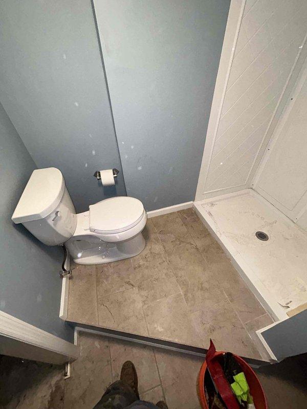 Completed under-sink plumbing repair in residential bathroom, removing existing drain assembly and P-trap. Installed new white PVC drain assembly with proper trap configuration, utilizing black rubber coupling to connect pipe sections. Accessed plumbing through cabinet opening, working within confined space beneath sink structure. Following installation, conducted thorough leak test to verify proper seal and drainage function. All connections secured and system restored to full operation.