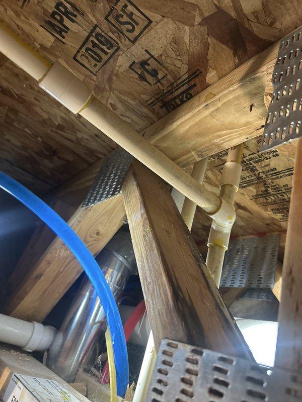 Responded to steady water leak reported in utility closet ceiling between units 218 and 219. Upon arrival, accessed attic crawl space and inspected exposed plumbing system, including PVC drain and vent lines running through ceiling joists. Documented conditions with photographs showing pipe routing, support strapping, and surrounding structural elements. Identified active dripping and traced source through visual inspection of pipe connections and joints in the affected area. Assessed installation of plumbing lines relative to insulation and radiant barrier materials to determine leak origin point.