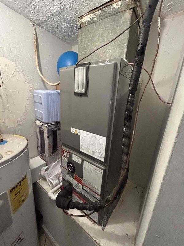 Completed full HVAC system installation including RUUD 2-ton heat pump (model RP14AY24AJ2NA), RUUD 2-ton air handler (model RH2TY2417STANNJ), and RUUD 5 kW heat kit (model RXBH-1724A05J-B) with digital thermostat. Installed outdoor heat pump unit on pad with snow legs, electrical whip kit, and disconnect box; applied refrigerant line insulation and installed refrigerant line filter. Mounted air handler in utility room with transition to existing ductwork, standard-sized air filter rack, and trap installation. Installed SS2 coil drain safety water sensor and "Ceiling Saver" overflow drain pan with water sensor for secondary protection. Completed all electrical connections, tested system operation, and verified proper refrigerant charge and airflow. System protected by 1-year labor warranty and 10-year parts warranty, with complimentary 1-year maintenance plan enrollment providing semi-annual inspections.