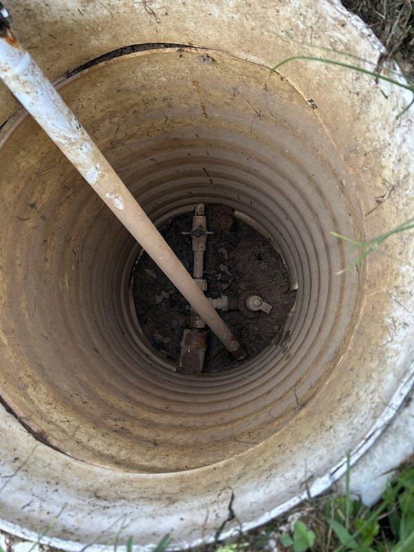 Responded to service call for leaking outdoor hydrant located in front of barn area. Upon arrival, confirmed hydrant had been experiencing active leak for extended period, with water supply currently shut off to prevent continued leakage. Inspected vintage red hand pump-style hydrant and associated underground piping accessed through concrete well shaft. Assessment revealed significant corrosion and deterioration of internal valve mechanisms and connecting pipes at base of unit within well structure. Documented existing conditions showing rust damage to metal components and aging infrastructure consistent with 21-year-old residential plumbing system. Provided recommendations for hydrant replacement and evaluation of underground water line integrity to restore proper function and eliminate leak source.