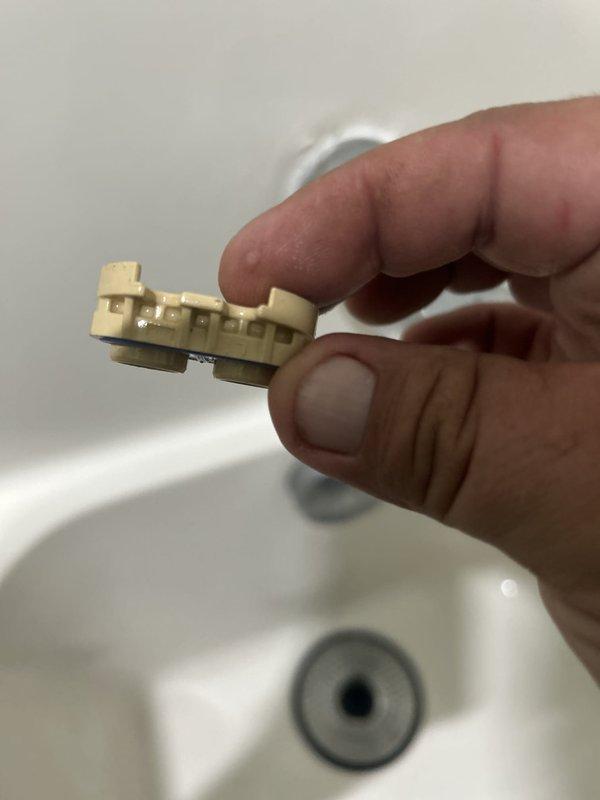 Responded to service call for leaking shower/tub valve issue. Upon inspection, identified failed diverter assembly components causing water leak. Removed and replaced defective plastic float mechanism and brass cartridge retainer from tub spout diverter valve. Photographed failed parts showing wear and deterioration of internal valve components. Tested system operation after replacement to verify proper function and confirm leak resolution.