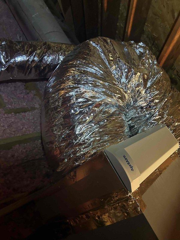 Responded to warranty call regarding whistling noise from geothermal system installed in February. Upon inspection, discovered flexible metallic ductwork in attic space was compressed and bunched, creating accordion-like configuration that was causing airflow restriction and whistling sound. Inspected HVAC duct system, junction box, and plenum connections throughout attic space. Documented existing installation conditions showing compressed flex duct, insulation placement, and system components. Identified improper duct installation as source of noise complaint.