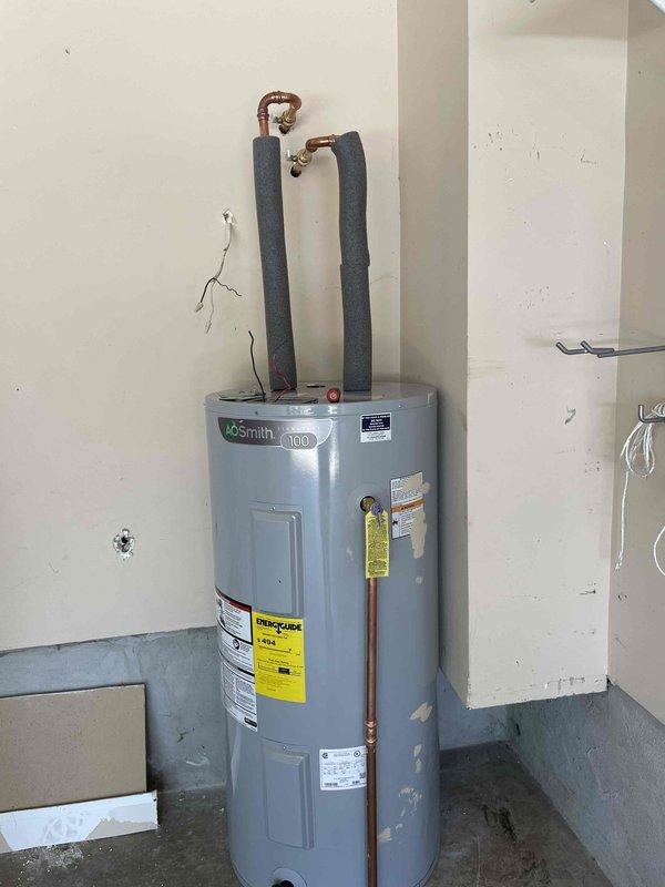 Successfully relocated AO Smith Signature 100 water heater from interior laundry area to garage to eliminate obstruction of washer box and improve utility room accessibility. Disconnected existing water supply lines, gas connections, and flue venting from original location, then reinstalled unit in garage with proper clearances per manufacturer specifications and local code requirements. Reconnected hot and cold water lines using copper piping with foam insulation, re-established gas service, verified all connections for leaks, and tested unit operation to ensure proper functionality in new location.